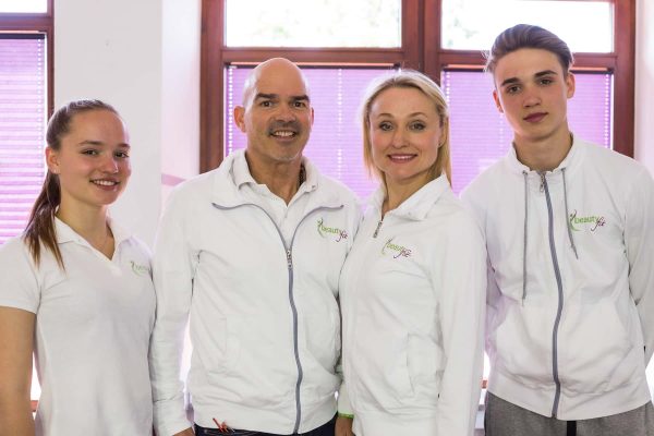 Vier Personen in weißen Jacken stehen lächelnd in einem Raum, bereit, Fragen als Personal Trainer zu beantworten.