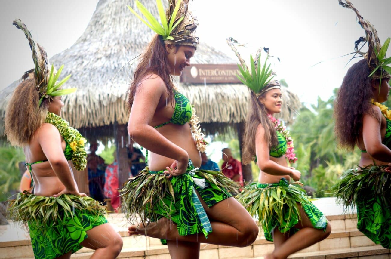 Frauen tanzen traditionell im Freien mit grünen Grasröcken und Blattkopfschmuck und zeigen positive Hula-Hoop-Wirkung.